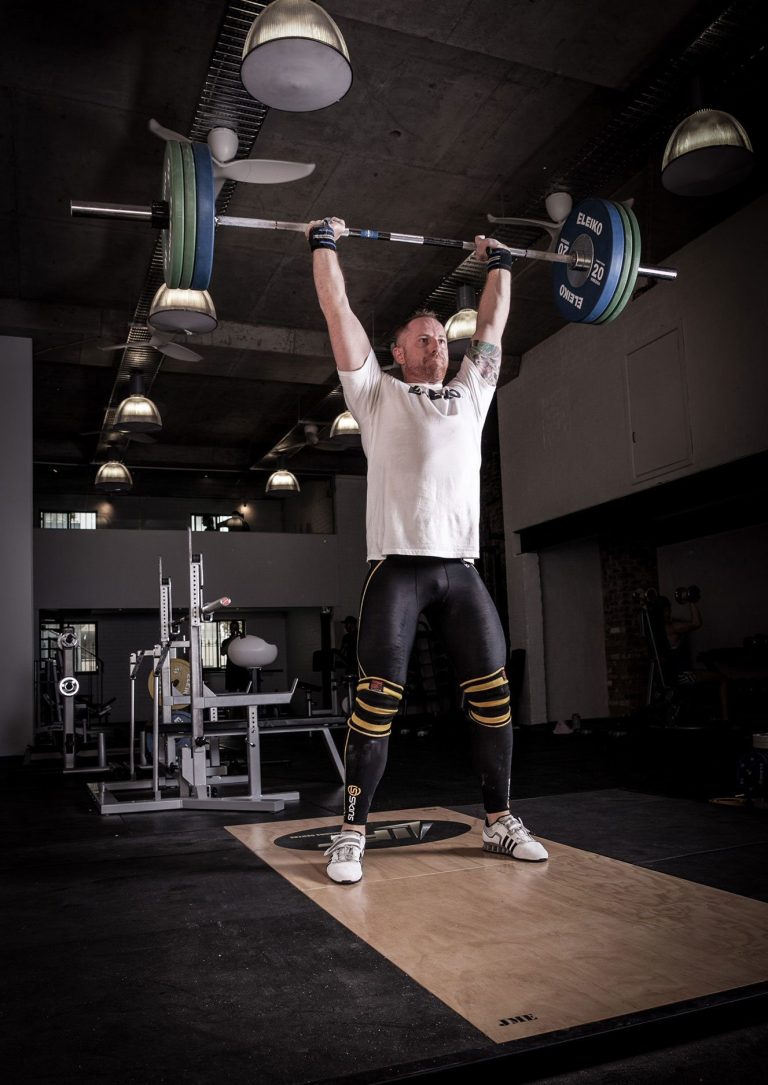 Picture of personal trainer Rhys Brooks performing an overhead press in a personal training gym in Sydney Australia